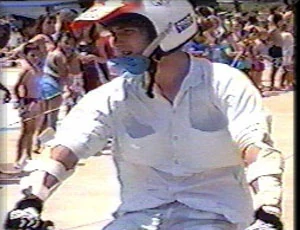 Kelly at nineteen, in helmet and pads, sitting on a blue bike in front of a crowd at the water park